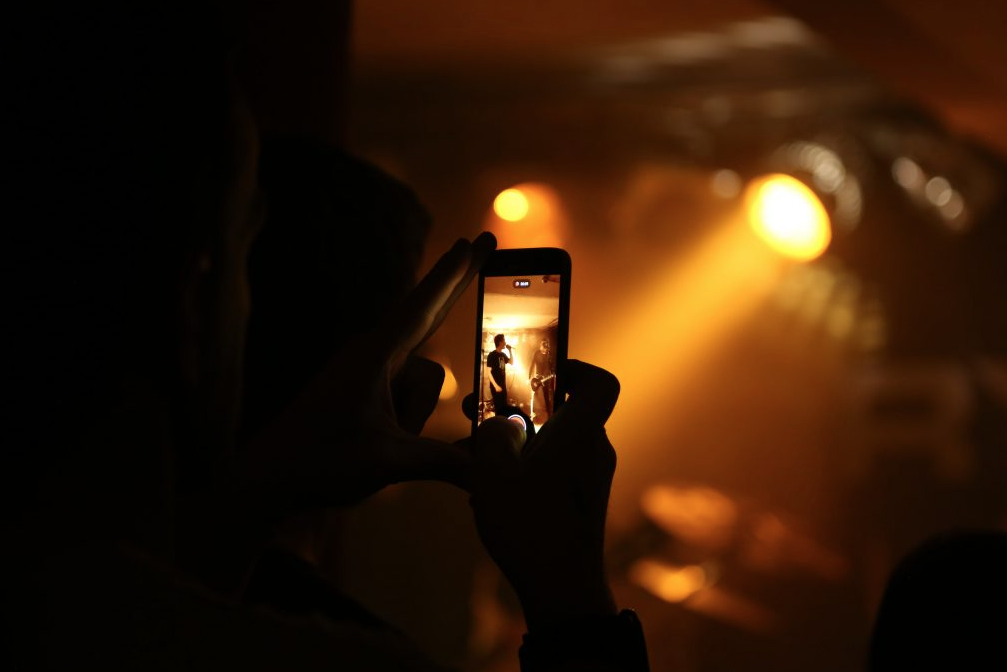 Ein Mensch fotografiert mit einem Smartphon ein Konzert