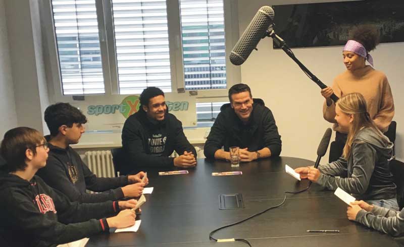 Teambesprechung an großem Tisch mit Mikrofon